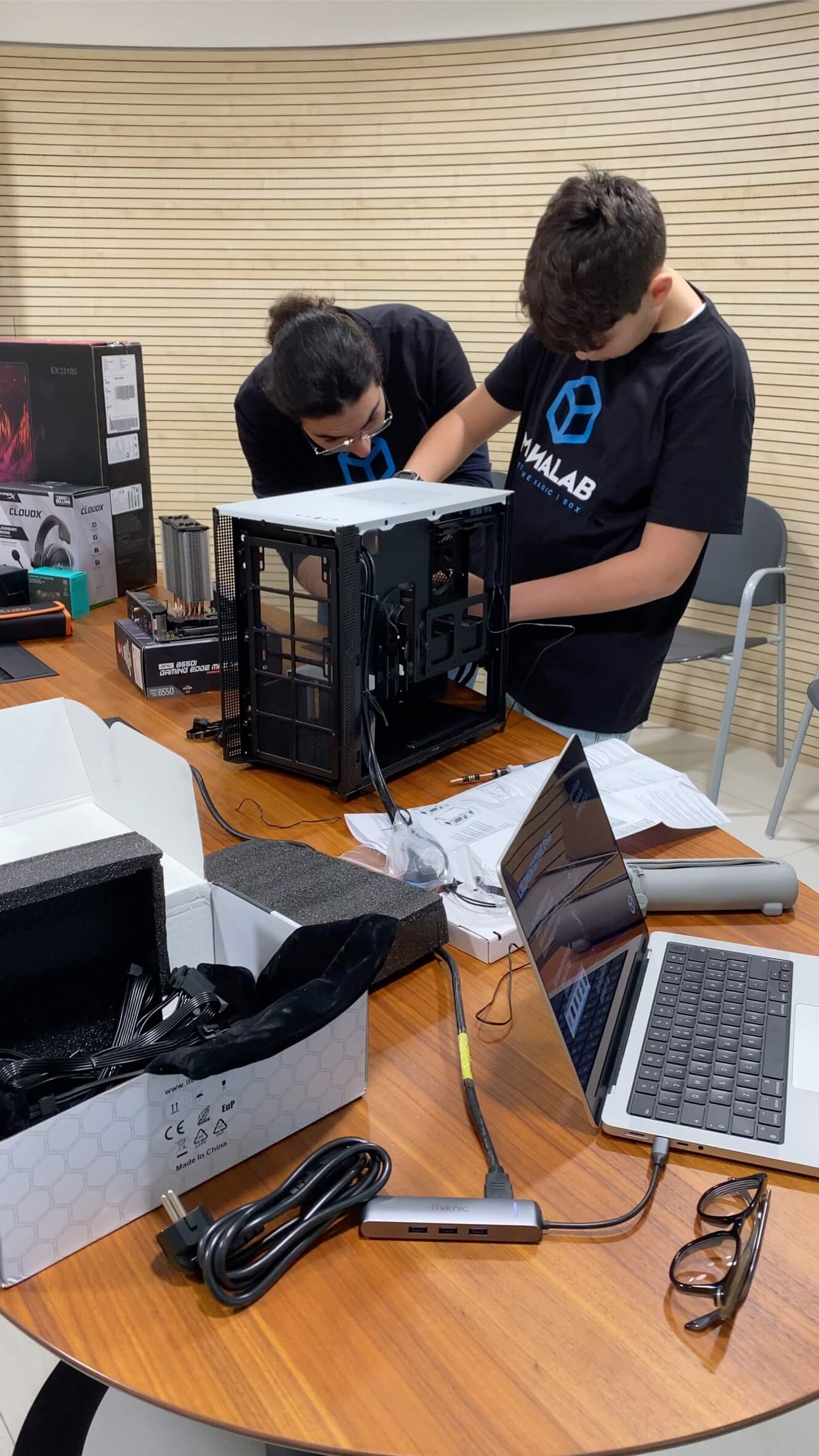 Due partecipanti assemblano un computer durante un laboratorio Mana